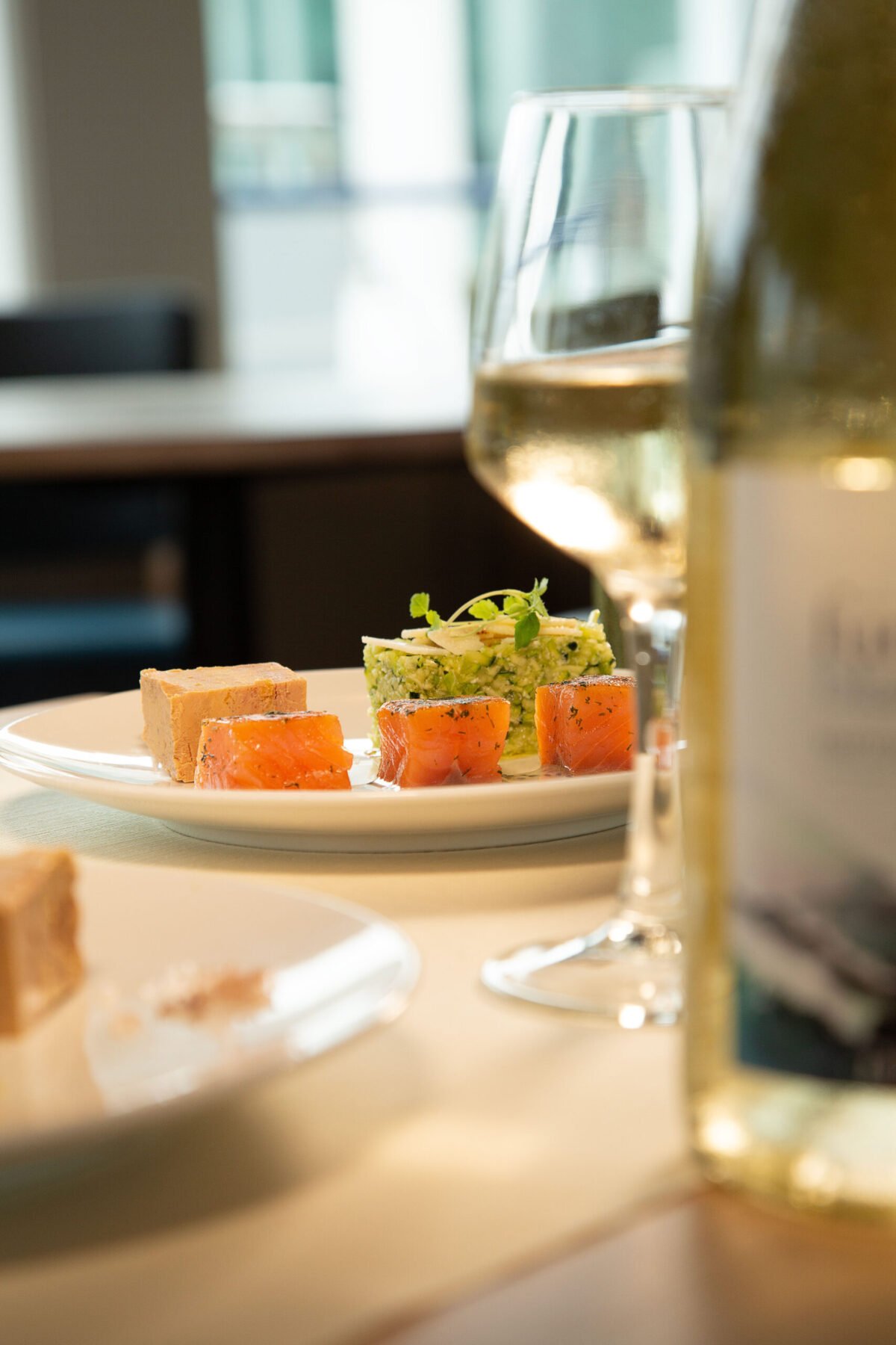 Entrée raffinée avec saumon et foie gras servie lors d'un dîner croisière sur la Seine à Paris, accompagnée de vin blanc | Le Capitaine Fracasse