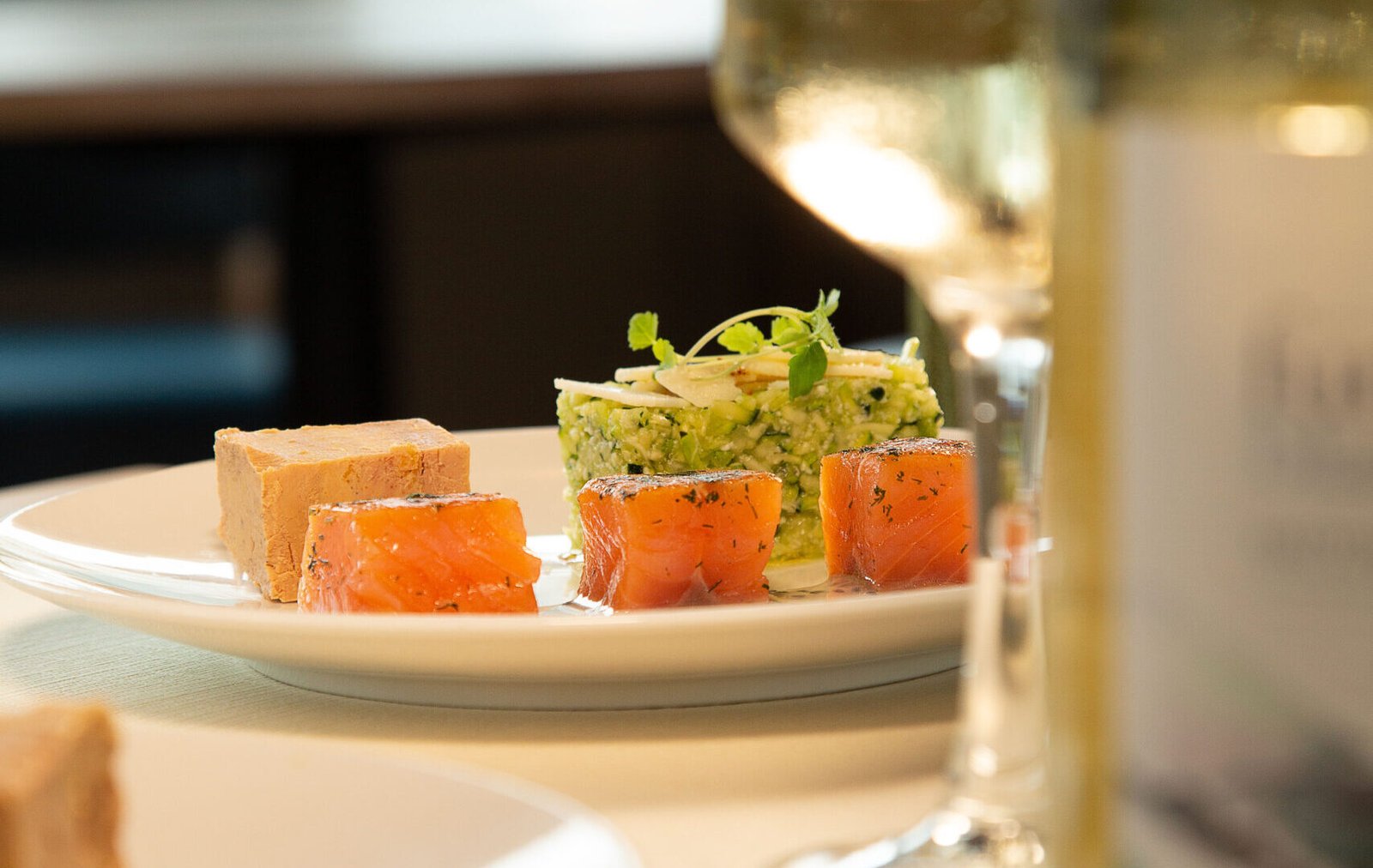 Entrée raffinée avec saumon et foie gras servie lors d'un dîner croisière sur la Seine à Paris, accompagnée de vin blanc | Le Capitaine Fracasse