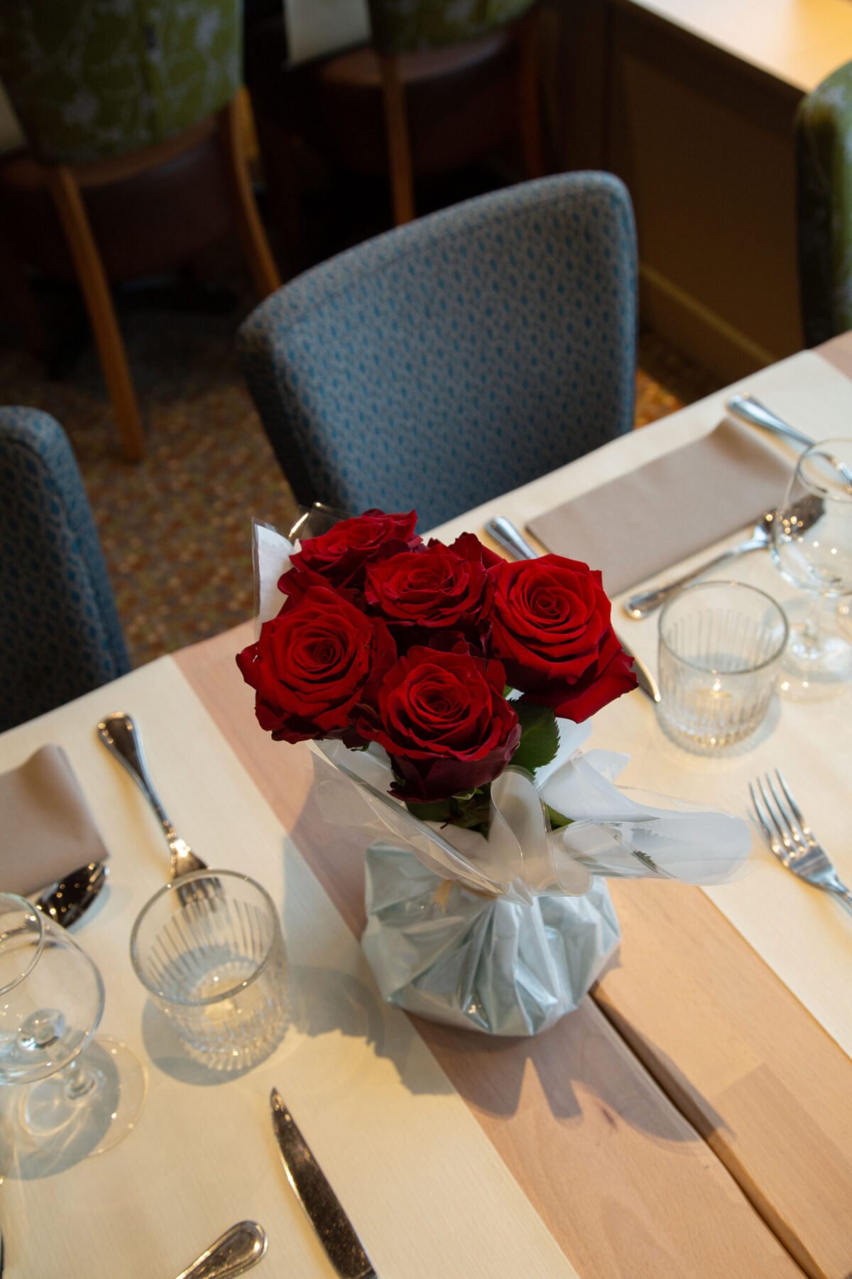 Table décorée avec un bouquet de roses rouges pour un dîner croisière romantique sur la Seine à Paris, offrant une vue sur un pont emblématique | Le Capitaine Fracasse